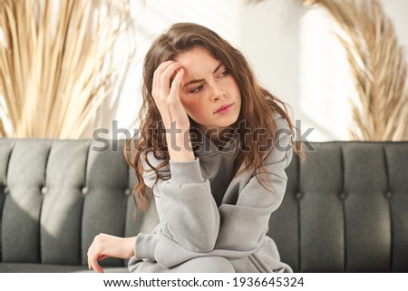 girl holding her head, woman has a headache. sad female sitting on couch