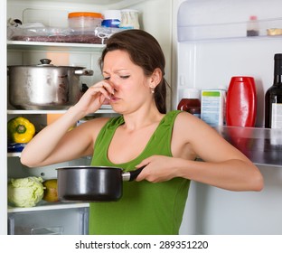 Girl Holding Her Nose Because Of Bad Smell From Food Near Refrigerator  At Home