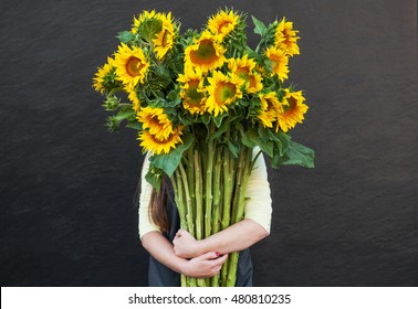 Girl Holding A Large Bouquet Of Sunflowers