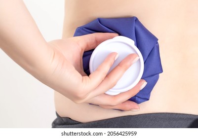 The Girl Is Holding A Medical Ice Bag Near The Injury On Her Back. Concept For The Treatment Of Bruise And Swelling After Body Trauma, Close-up