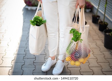 Girl is holding mesh shopping bag and cotton shopper with vegetables without plastic bags at farmers market. Zero waste, plastic free concept. Sustainable lifestyle. Banner