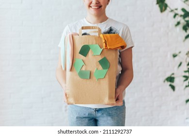 Girl holding paper bag with old clothes for recycling. - Shutterstock ID 2111292737