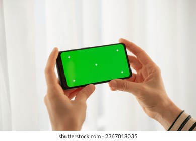 girl holding a phone with a green screen at home. Device. Smartphone. Social networks - Powered by Shutterstock