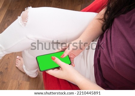 The girl is holding a phone with a green screen. Phone with green chrome key