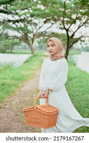 A Girl Holding A Picnic Basket And Peony Flower In Central Park. Selective Focus. Ready For Brunch Or Lunch.