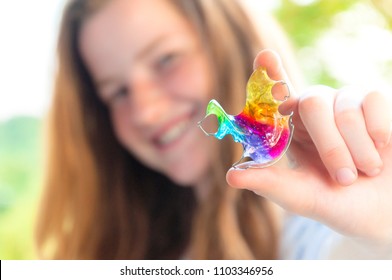 Girl Holding Rainbow Coloured Orthodontic Retainer