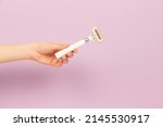 girl holding razor in hand on pink background