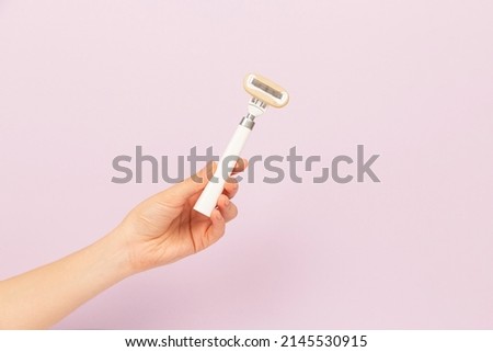 girl holding razor in hand on pink background