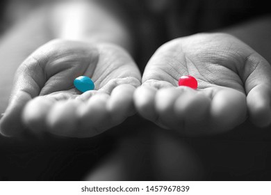 A Girl Holding A Red And A Blue Jelly Bean In Her Palms.