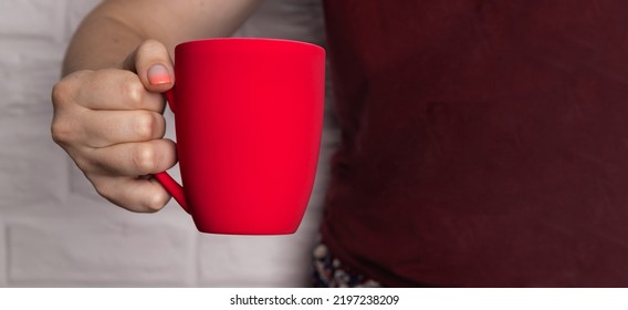 The Girl Is Holding A Red Mug. Place For Copy Space. Mug Mockup