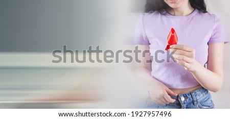 girl holding red ribbon sign cancer