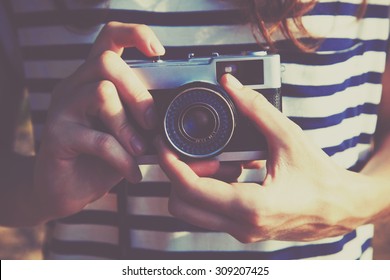 girl holding retro camera and taking photo
