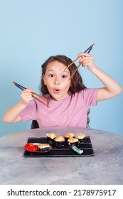 The Girl Holding Rolls Have A Face Like Binoculars. Japanese Cuisine Home Delivery. On A White Background In An Orange Dress. Long Curly Hair. It Is Ridiculous And Stupid.