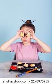 The Girl Holding Rolls Have A Face Like Binoculars. Japanese Cuisine Home Delivery. On A White Background In An Orange Dress. Long Curly Hair. It Is Ridiculous And Stupid.