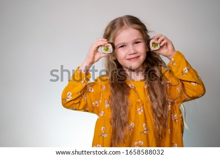 Girl holding rolls have a face like binoculars. Japanese cuisine home delivery. On a white background in an orange dress. Long curly hair. It is ridiculous and stupid.