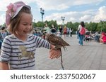 Girl holding small owl while standing in park against sky