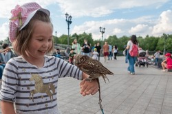 Girl Holding Small Owl While Standing In Park Against Sky