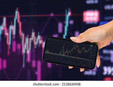 Girl holding a smartphone with financial stock market graph on t - Shutterstock ID 2118636908