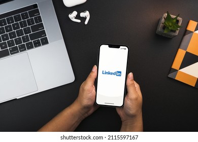 Girl holding a smartphone with Linkedin app on the screen on black background table. Office environment. Rio de Janeiro, RJ, Brazil. January 2022.