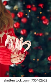 Girl holding stack of peppermint candy canes. Christmas holiday concept. Holiday background. Vertical