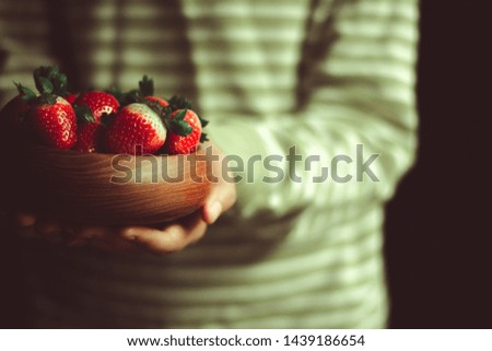 girl holding strawberries in a wooden bowl