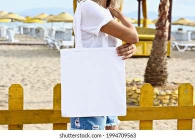 Girl Is Holding Tote Bag Canvas Fabric For Mockup Blank Template Isolated On Beach And Sea Background.