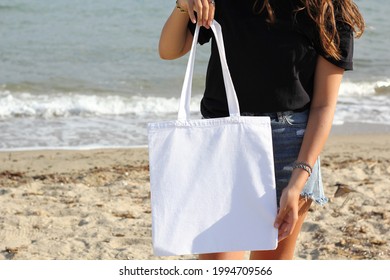 Girl Is Holding Tote Bag Canvas Fabric For Mockup Blank Template Isolated On Beach And Sea Background.