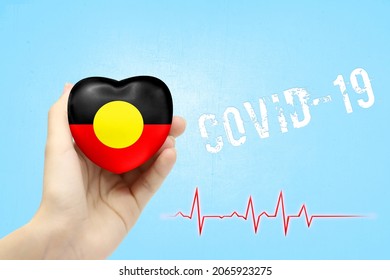 A Girl Is Holding A Toy In The Shape Of A Heart With The Flag Of Australian Aboriginal, A Concept Of Health Care During The Covid-19 Coronavirus Pandemic