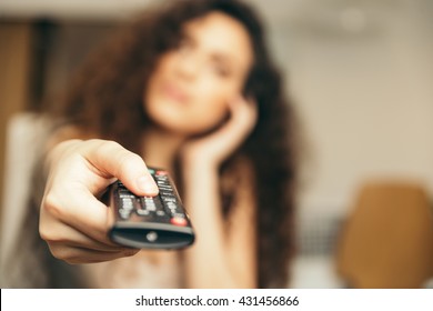 Girl Holding A TV Remote, Changing The Channel. Sexy Woman Sitting At Home With The Remote Control Watching Television Alone.