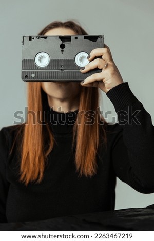 Girl holding a VHS cassette in front of her face
