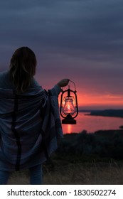 niña sosteniendo una lámpara de queroseno vintage en su mano al atardecer