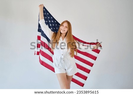 Girl holds the American flag on a light background. Independence Day concept. A woman celebrates a national holiday