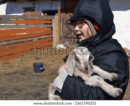 A girl holds an Anglo-Nubian goat in her arms. Love for pets