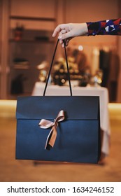 Girl Holds Beautiful Dark Blue Gift Bag With A Pink Bow. Special Evening With Presents. Valentine's Day Or Women's Day.