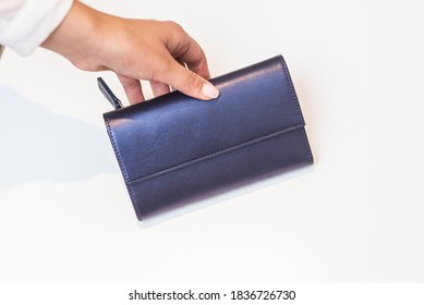 Girl Holds Blue Purse On White Table