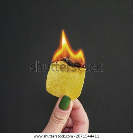the girl holds burning chips. the flame in a woman's hand. burning harmful and extra calories. square image