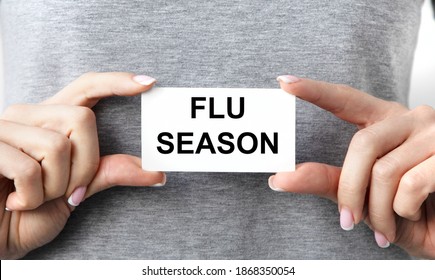 The Girl Holds A Business Card With The Text FLU SEASON In Front Of Her Two Hands.