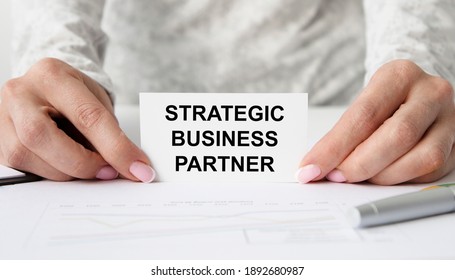 A Girl Holds A Card With A Strategic BUSINESS PARTNER.