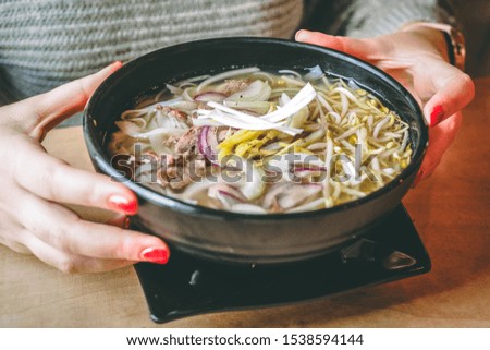 
Girl holds in a hands a bowl of Vietnamese pho soup 
