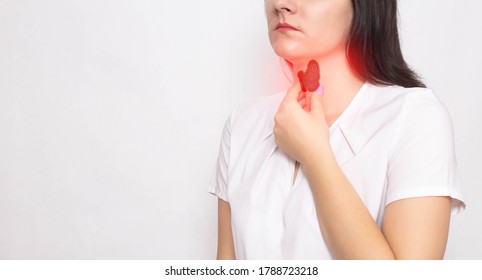 The Girl Holds Her Neck With A Thyroid Gland With Her Hand On A White Background. Thyroid Diseases And Problems Concept, Lack Of Iodine In The Body, Copy Space For Text