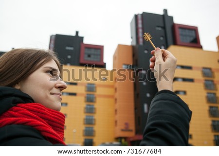 a girl holds the keys to the apartment on the background of new buildings