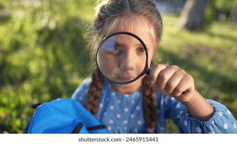 the girl holds magnifying glass in her hands. gaining knowledge and curiosity concept. a schoolgirl girl with a black magnifying glass is lifestyle examining something, park on the background - Powered by Shutterstock