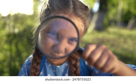 the girl holds magnifying glass in her hands. gaining knowledge and curiosity concept. a schoolgirl girl with a black magnifying glass is examining something, park on the lifestyle background - Powered by Shutterstock