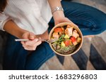 Girl holds a paper plate with healthy food sitting on the floor. Home delivery food. Healthy eating concept. When you stay at home.