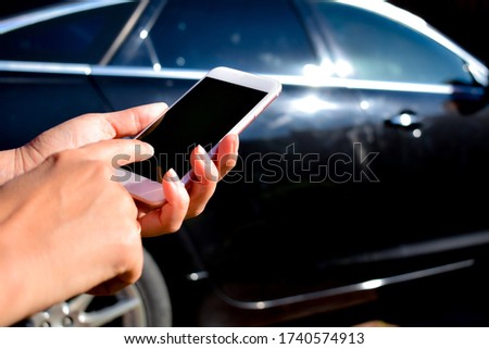 Girl holds a smartphone in hand on background a black car