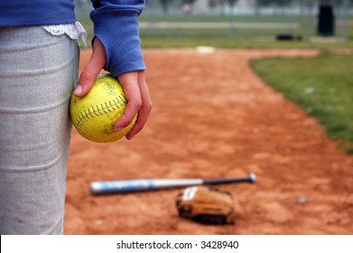 A Girl Holds A Softball On The Infield Diamond.