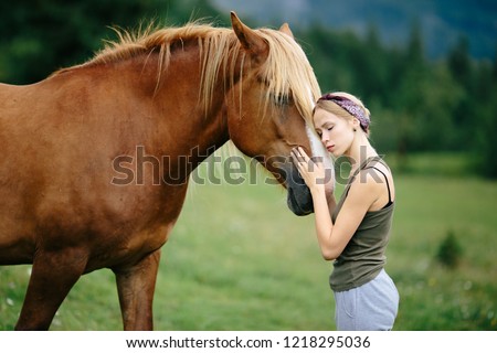 Girl And horse. Beautiful girl hugs her horse. Girl wth closed eyes pats her horse. Brown Horse and her owner