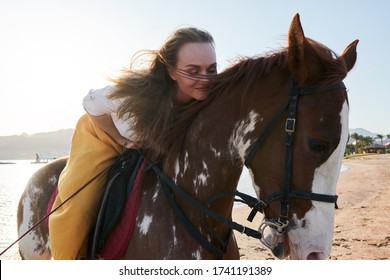 Girl horseback rider sitting on a horse stroking horse's neck