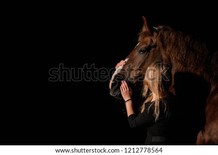 girl hugging a horse on a dark background