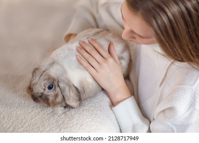 Girl Hugs A Cute White Rabbit At Home.a Girl With A Rabbit, Bunny Pet. Close Up